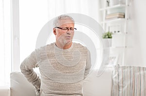 Unhappy senior man suffering from backache at home