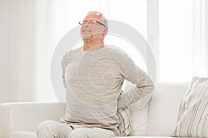 Unhappy senior man suffering from backache at home