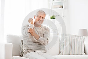 Unhappy senior man suffering elbow pain at home