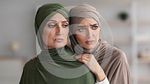 Unhappy Senior Muslim Lady And Her Adult Daughter Embracing Indoor