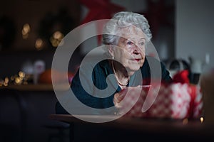 Unhappy senior woman sitting alone and waiting for family during Christmas Eve.Concept of solitude senior and mental