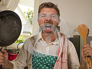 Unhappy and stressed man in kitchen apron feeling frustrated and upset overwhelmed by domestic chores washing dishes tired