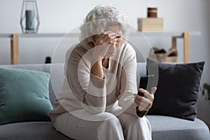 Unhappy stressed mature middle aged woman looking at phone screen photo