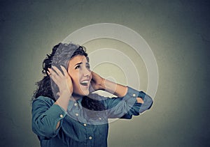 Unhappy stressed woman covering her ears looking up stop making loud noise