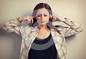 Unhappy stressed young woman not want to listen and covering the