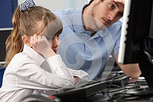 Unhappy teacher and girl using computer in class