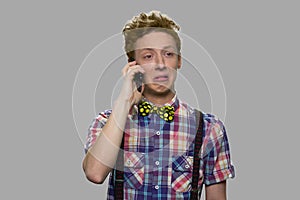Unhappy teen boy talking on cell phone.