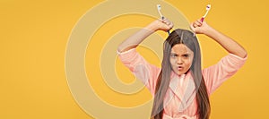 unhappy teen girl in home terry bathrobe hold toothbrush as devils horns, bathroom fun. Banner of child girl with teeth