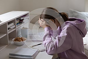 Unhappy teen girl stressed studying at home