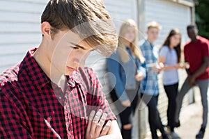 Unhappy Teenage Boy Being Gossiped About By Peers