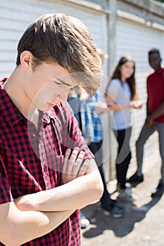 Unhappy Teenage Boy Being Gossiped About By Peers