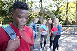 Unhappy Teenage Boy Being Gossiped About By School Friends