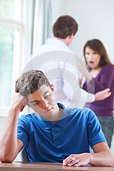 Unhappy Teenage Boy With Parents Arguing In Background