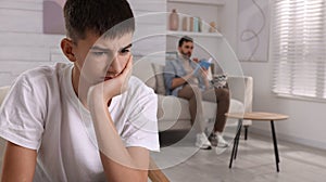 Unhappy teenage boy suffering from lack of father`s attention in living room. Problems at home