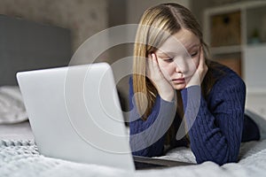 Unhappy Teenage Girl With Laptop Lying On Bed At Home Anxious About Social Media Online Bullying And Using Phone Too Much