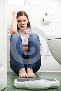 Unhappy Teenage Girl Looking At Bathroom Scales