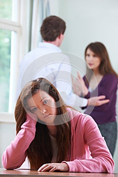 Unhappy Teenage Girl With Parents Arguing In Background