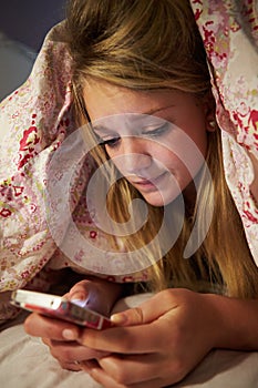 Unhappy Teenage Girl Sending Text Message Whilst Lying In Bed