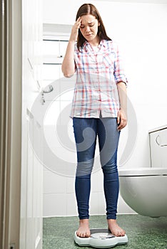 Unhappy Teenage Girl Standing On Bathroom Scales