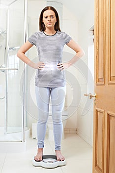 Unhappy Teenage Girl Standing On Bathroom Scales