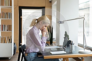 Unhappy thoughtful businesswoman solving problem, sitting at work desk