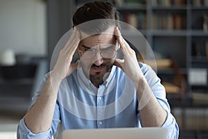 Unhappy tired businessman touching temples, working on difficult task