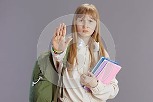 unhappy trendy teen girl with backpack showing stop gesture