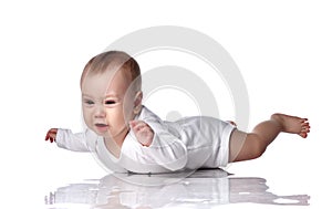 Unhappy upset infant baby boy toddler in diaper and white bodysuit is lying on floor on his stomach and crying