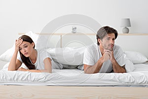 Unhappy upset offended angry millennial european wife and husband lying on bed, ignoring partner