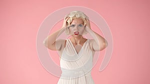 An unhappy upset woman is holding her head. Woman feels ill from tension, migraine, fatigue. Woman in image of Marilyn