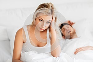 Unhappy woman in bed with snoring sleeping man