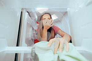 Unhappy Woman Cleaning Stinky Dirty Fridge with a Cloth