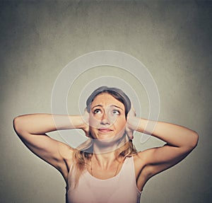 Unhappy woman covering her ears looking up stop making loud noise