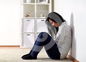 Unhappy woman crying on floor at home