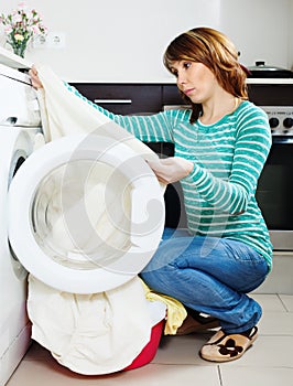 Unhappy woman doing laundry with washing machine