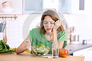 Unhappy woman eating vegetable salad