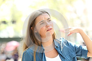 Unhappy woman fanning with the hand suffering heat stroke photo