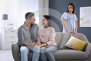 Unhappy woman feeling jealous while couple spending time together at home