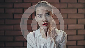 Unhappy woman feeling sore throat and coughing on brick wall background