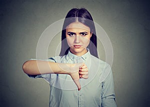 Unhappy woman giving thumbs down gesture looking with negative expression