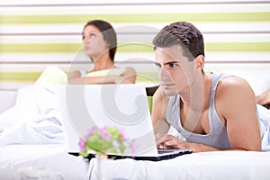 Unhappy woman because his husband working in bed