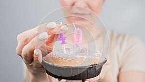 Unhappy woman holding a cake with candles for her 40th birthday. The girl cries about the loss of youth. photo