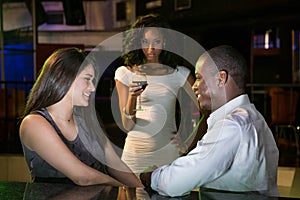 Unhappy woman looking at a couple flirting near bar counter