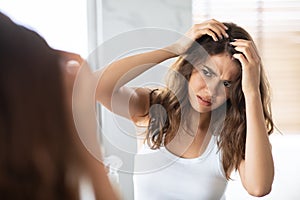 Unhappy Woman Looking At Hair Flakes Having Dandruff Problem Indoor