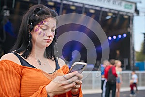 Unhappy Woman Looking At Mobile Phone Trying To Meet Friends At Outdoor Summer Music Festival 