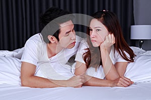 Unhappy woman lying on bed with a concerned guy comforting her