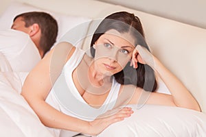 Unhappy woman lying in bed stressed.