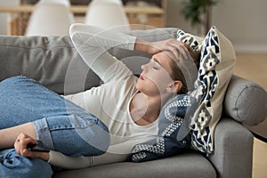 Unhappy woman lying on couch at home