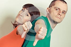 Unhappy woman and man showing thumbs down. Negative emotions concept