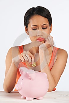 Unhappy Woman Putting Coin Into Piggy Bank